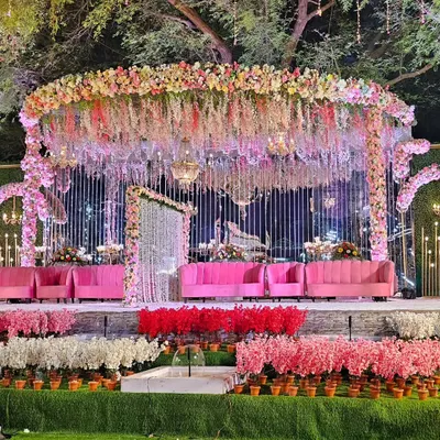 A full view of the extravagant floral stage, showing how the elevated platform and lush foreground arrangements create a multi-layered, immersive setting. This design is perfect for large outdoor venues like Lokhandwala Garden.