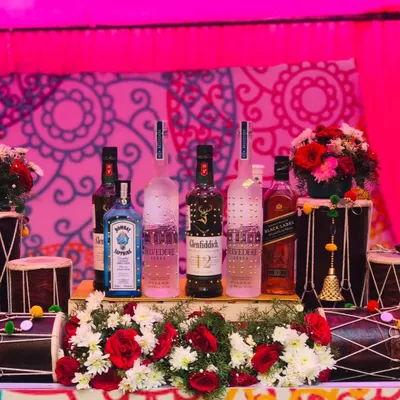 The centerpiece of my 'Funjabi' themed bar. Premium liquor bottles are artfully arranged on a bed of flowers, flanked by two traditional dhols, perfectly capturing the celebratory spirit of a Punjabi wedding.