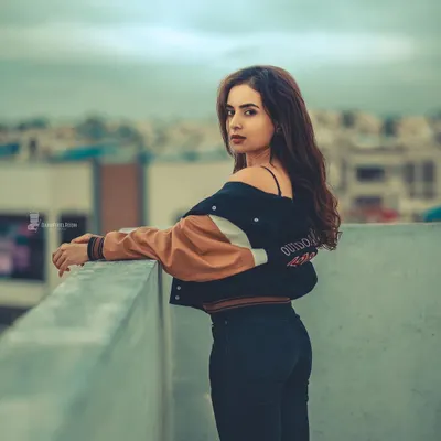 A classic rooftop portrait with a moody, cinematic edit. The city skyline and overcast sky create a dramatic backdrop that emphasizes the subject's presence.