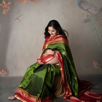 A portrait of traditional elegance. This mom-to-be looks absolutely stunning in a green and red silk saree, gently cradling her baby bump.