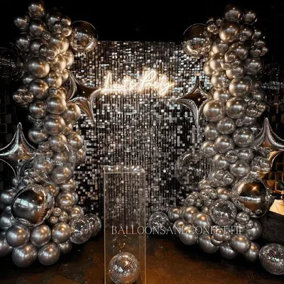 This is the definition of a party backdrop. A silver sequin wall, chrome balloon garlands, star-shaped foil balloons, and disco balls come together for a high-energy, disco-glam vibe.