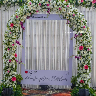 We create fun, interactive photo opportunities like this custom Instagram frame, adorned with a lush arch of white and pink flowers, personalized with the couple's handle and hashtag.