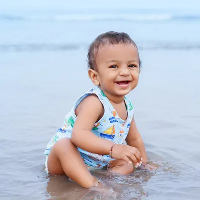 A baby boy's joyful smile as he sits in the shallow water at the beach. This is what pure, simple happiness looks like.
