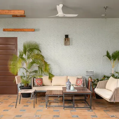 This covered patio on a terrace is designed as an extension of the living room. With terracotta tiles, comfortable seating, and surrounding plants, it's a perfect spot for relaxing or entertaining.