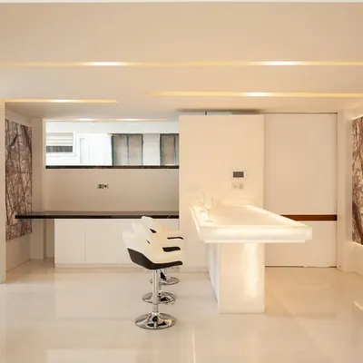 a minimalist breakfast counter crafted from a single piece of backlit onyx, providing a warm, ambient light source… paired with modern, sculptural bar stools.