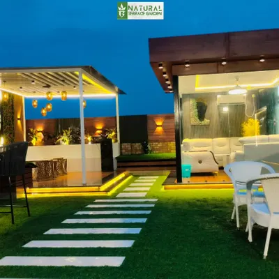 A stunning night view of our completed project in Shahdara, New Delhi. The entire terrace is illuminated, highlighting the glass house, pergola, and lush artificial lawn.