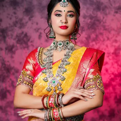 A studio portrait focusing on a model in a stunning yellow and red Kanchipuram silk saree. The focus is on the rich colors, heavy silver jewelry, and the model's confident and regal posture.