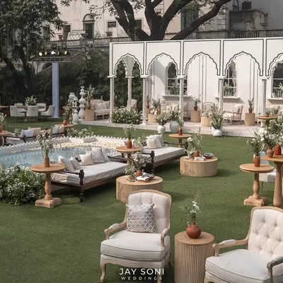 I designed this expansive outdoor lounge to feel like a luxurious garden retreat. The space features a mix of classic upholstered armchairs, traditional daybeds, and a serene water feature, all unified by a chic ivory and white color palette.