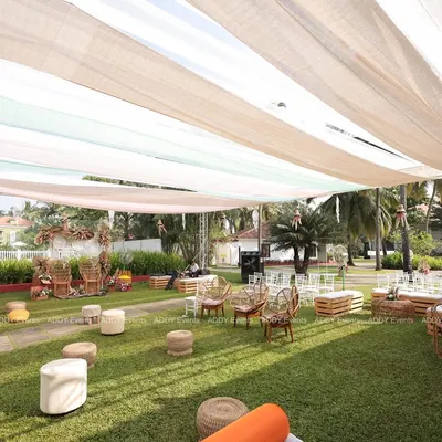 This wide view showcases a complete boho-themed outdoor Mehndi setup. We used a mix of rattan chairs, low poufs, and wooden crate tables under a flowing fabric canopy to create a relaxed and stylish lounge area for guests.
