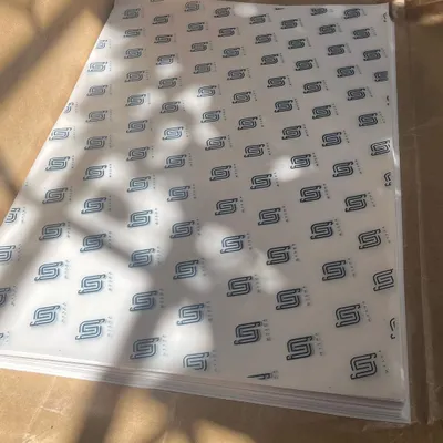 A stack of freshly printed custom wrapping paper for the clothing brand Mysha. A repeating logo pattern creates a strong, professional brand impression right from the packaging.