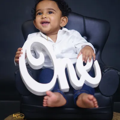 He is ONE. A classic first birthday portrait with the baby sitting in a miniature armchair, holding the "ONE" sign. Simple, elegant, and timeless.