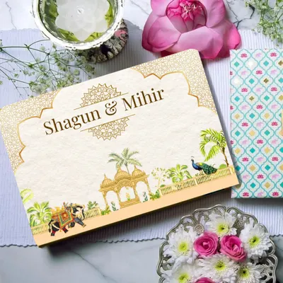 This is the top of the custom 'Shagun & Mihir' invitation box, featuring a royal Indian theme with intricate gold details, peacocks, and illustrated elephants. It sets the tone for a grand and traditional wedding celebration.