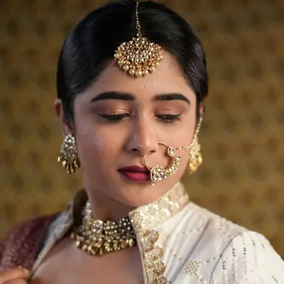 A detailed shot of a classic, retro-inspired makeup look. I used soft brown eyeshadow and a deep red lip, paired with traditional jewelry like a maang tikka and nath, to create a timeless and elegant aesthetic.