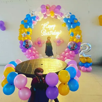 Yeh Frozen theme par second birthday party ki decoration hai. Ismein humne Anna aur Elsa ke cutouts, theme ke color ke balloons ka ring, aur '2' number ka foil balloon use kiya hai.
