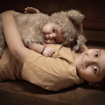 The beginning of a lifelong friendship. This tender moment shows an older brother lovingly cuddling his new baby sibling, who is dressed in an adorable bear costume.