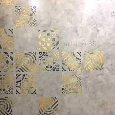 A close-up of the metallic gold stencils on a grey textured base. You can see how the light catches the different patterns, creating a dynamic and luxurious effect for this bedroom wall.