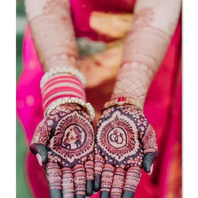 A perfect engagement mehendi with the couple's portrait in one palm and interlocking rings in the other. The dark stain looks beautiful against the bride's pink saree.