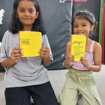 Two young girls proudly display the books they made themselves in our bookbinding workshop. The sense of accomplishment from creating something with your own hands is priceless.