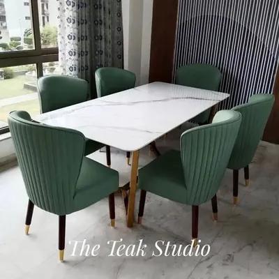 A beautiful six-seater set featuring a white marble tabletop with subtle grey veining. The plush, channel-tufted green velvet chairs add a pop of color and sophistication, while their tapered legs with gold-finished tips complete the luxurious look.