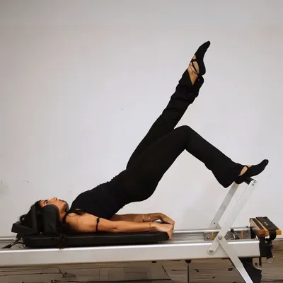 The reformer isn't just a machine, it's a full-body wake-up call. This client is performing a shoulder bridge with leg extension, a move that strengthens the entire back of the body.