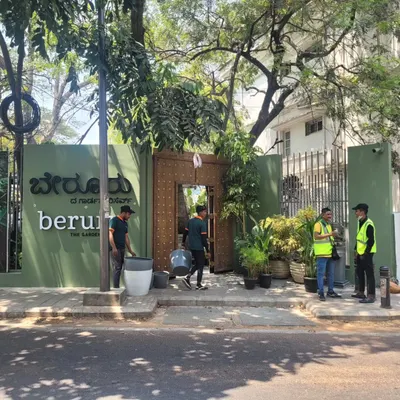 The entrance to the Beruru flagship store on Lavelle Road, designed to feel like you are stepping into a hidden garden. The large wooden door and surrounding greenery create a sense of discovery and transition from the busy street.