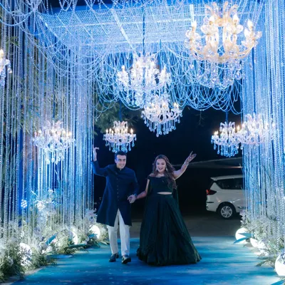 The grand entrance to a sangeet under the stars. Guests walked through a tunnel of shimmering blue light and crystal strings, flanked by chandeliers, setting the tone for a magical night at Oleander Farms.