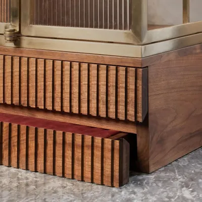A well-crafted detail is a joy to discover. This image shows the fine fluting on a solid wood drawer, which contrasts beautifully with the smooth brass frame and the rich walnut of the main cabinet.