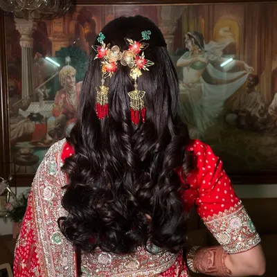 A beautiful half-updo with soft curls, adorned with ornate, dangling hair accessories. This hairstyle is perfect for a Sangeet or wedding ceremony, adding a touch of royalty to the look.