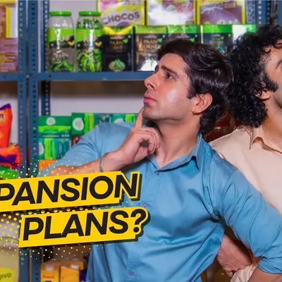 A promotional still from a business loan ad series for Shriram Finance, featured during the Cricket World Cup. This shot captures a moment of consideration between two business partners, designed for a high-visibility ad campaign.