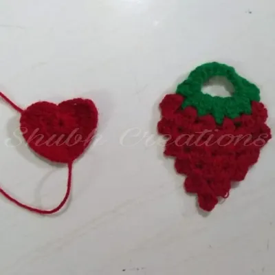 Two small crochet appliqués, a simple red heart and a strawberry top, showing how I create small decorative elements.