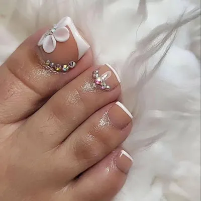An elegant pedicure design perfect for a bride or special occasion. This look features a classic white French tip, accented with a beautiful 3D sculpted flower and delicate rhinestone placements.