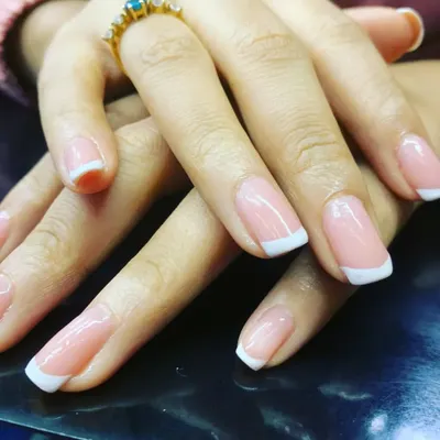 A flawless execution of the classic French manicure. This close-up highlights the perfectly shaped nails, the clean white tips, and the glossy finish that make this style a timeless favorite.
