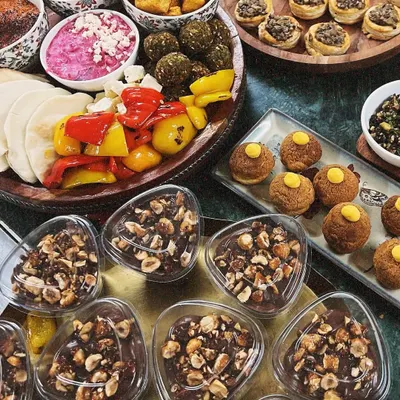 An abundant spread of our Mediterranean and Italian-inspired platters. This setup includes a mezze platter with falafel and hummus, mushroom vol-au-vents, a caprese board, and chocolate hazelnut mousse cups.