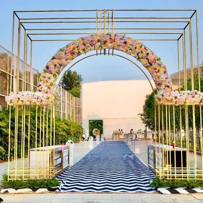 We love making a grand entrance. For this 60th birthday, we fabricated this stunning golden geometric archway, decorated with a lush floral arrangement, to welcome guests over a custom black and white chevron-patterned walkway.