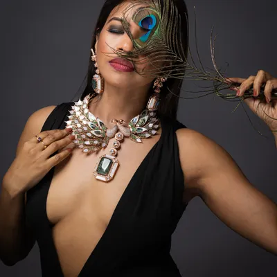 A creative and luxurious shot featuring a grand peacock-themed statement necklace. The use of a real peacock feather adds a layer of artistry to this high-end jewellery photograph.