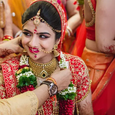 A candid moment during the wedding ceremony as the groom places the varmala on his smiling bride. Her expression of pure happiness is the focus of this beautiful shot.