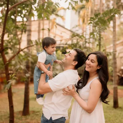 Pure joy and laughter in the park. An outdoor family session is perfect for capturing candid moments like this, with dad lifting his little one high in the air.