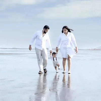A family of three enjoying a walk on a serene Mumbai beach during their outdoor photoshoot. The natural, open environment allows for relaxed and authentic family portraits with beautiful reflections and light.