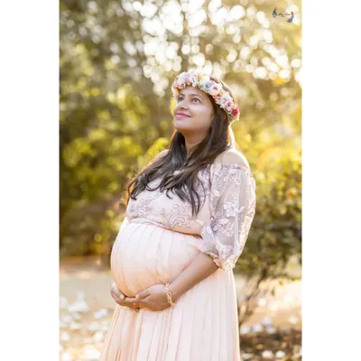 Bathed in warm, golden light, the mother-to-be looks up with a hopeful expression. This portrait, featuring one of my rental gowns and a floral tiara, captures the beautiful dream of motherhood.