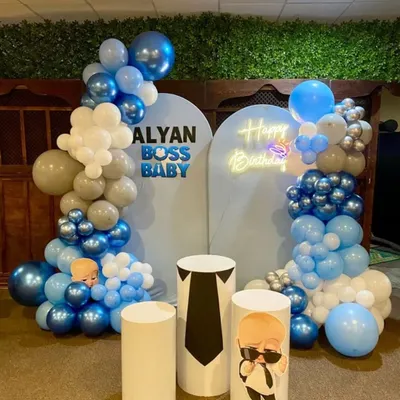 The Boss Baby has arrived! This stylish birthday setup features two backdrops, custom-printed pedestals, a neon "Happy Birthday" sign, and a cool blue, white, and silver balloon garland.