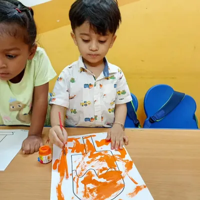 Life is a big canvas! A young artist is completely absorbed in painting the letter 'U', exploring colors and shapes with focus and creativity.