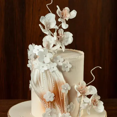 This single-tier cake from my Ruffle Paper Collection showcases delicate, paper-thin ruffles and a spray of handmade white sugar flowers. The design is elegant and minimalist, perfect for an intimate wedding or anniversary.