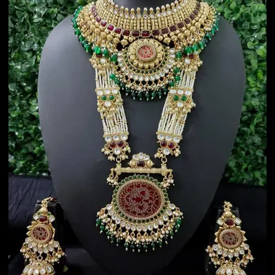 This is the ultimate statement of bridal luxury. A grand rental set featuring a detailed choker and a magnificent rani haar with red engraved pendants, green beads, and matching jhumkas.