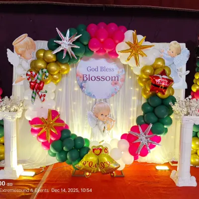 A unique Christmas-themed decoration for a Christening ceremony. The balloon ring backdrop includes festive colors, stars, angels, and other Christmas elements.