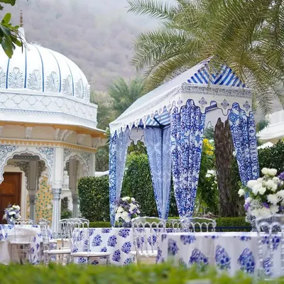 A stunning view of the event setup at The Leela Palace, Jaipur. The custom-designed canopy and tables, featuring blue and white prints, stand beautifully against the palace's architecture.