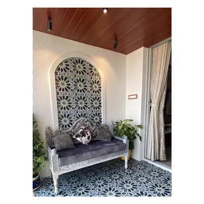 I transformed this balcony into a Moroccan-inspired retreat. The beautiful blue and white patterned tiles on the floor and in the arched wall niche are the main feature. A traditional carved bench and a warm wooden ceiling complete this cozy outdoor lounge.