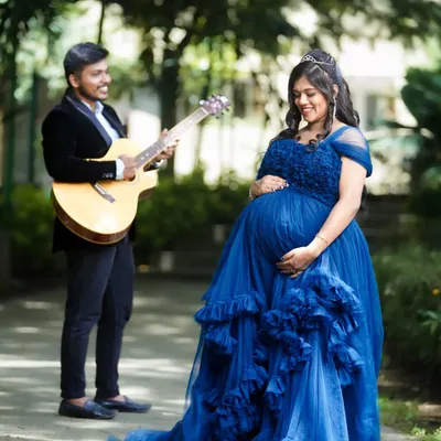 A creative maternity shoot where the father-to-be serenades his wife with a guitar. This photo tells a story and captures the love and anticipation of the couple in a beautiful outdoor setting.