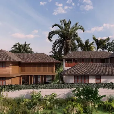 An exterior rendering of the Morjim villa complex, showcasing two distinct architectural styles. On the left, a villa with wooden elements, and on the right, a home built with the characteristic local laterite stone, both unified by a vernacular Goan design language.