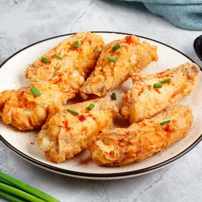 A plate of our classic Fried Chicken Wings, golden-brown and crispy on the outside while remaining juicy inside. Served with ketchup for dipping.