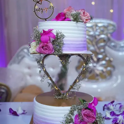 This beautiful two-tier engagement cake was a dream to create. The floating heart stand adds a touch of magic, and the fresh flowers in shades of purple and pink make it so romantic.